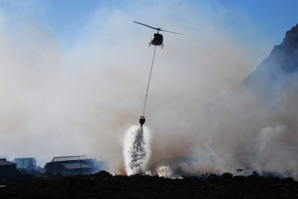 An image showcasing a serene landscape with lush greenery and a pristine river, juxtaposed with a team of technicians utilizing eco-friendly equipment to restore fire-damaged buildings, emphasizing sustainability and environmental consciousness