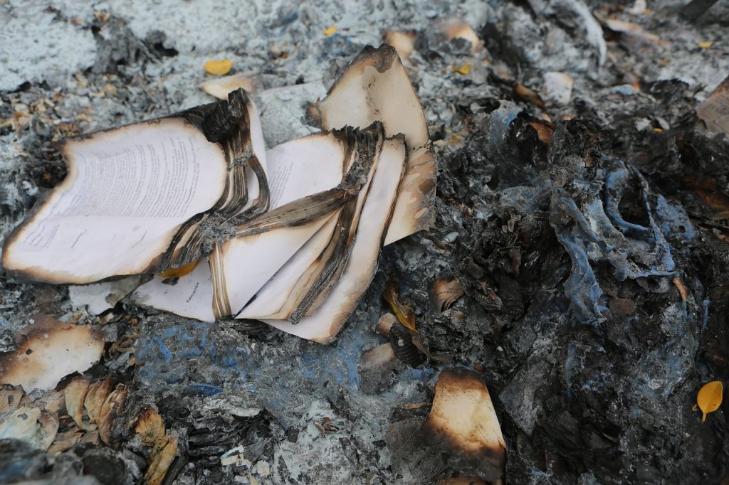 An image showcasing the aftermath of a devastating fire: a charred home with blackened walls, broken windows, and remnants of belongings scattered amidst the debris—symbolizing the resilience and restoration in Trial By Fire: A Real-Life Fire Damage Restoration Story